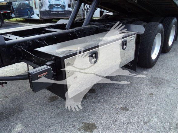Truck chassis with storage boxes under the flatbed on a Peterbilt 367, dual rear wheels visible.