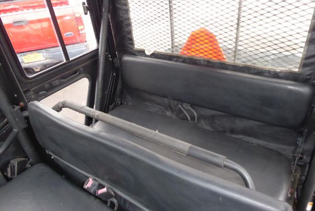 Truck bed interior of 2011 Kawasaki KAF950G showing seating area with protective cage mesh and rear bench seats.