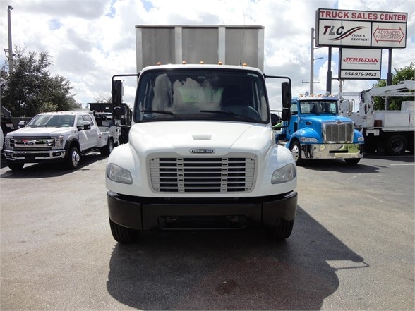  Freightliner Business Class M2 106 front view showing white cab, grille, headlights, and bumper in a truck dealership lot.
