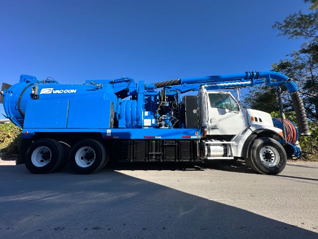 2005 Sterling L7500 vacuum truck side view with blue Vac-Con unit, white cab, large extraction hose, and storage compartments.