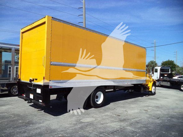 Box truck body in yellow with metal side rails and white wheels, long cargo area, parked in a lot.