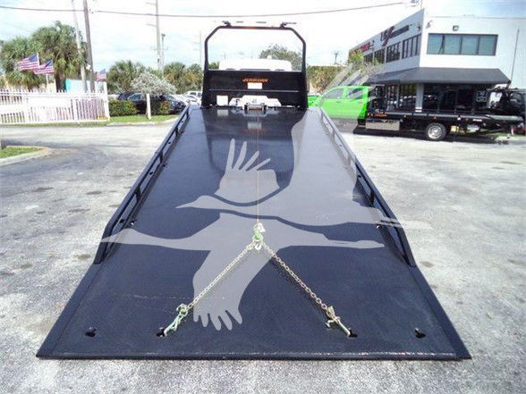 Kenworth T280 truck flatbed with a black ramp and chains securing it, viewed from above in a dealership lot.