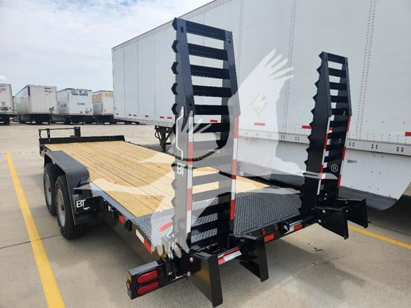 Trailer flatbed with power ramps at rear, wooden deck and dual axle, Behnke brand trailer in a parking lot.