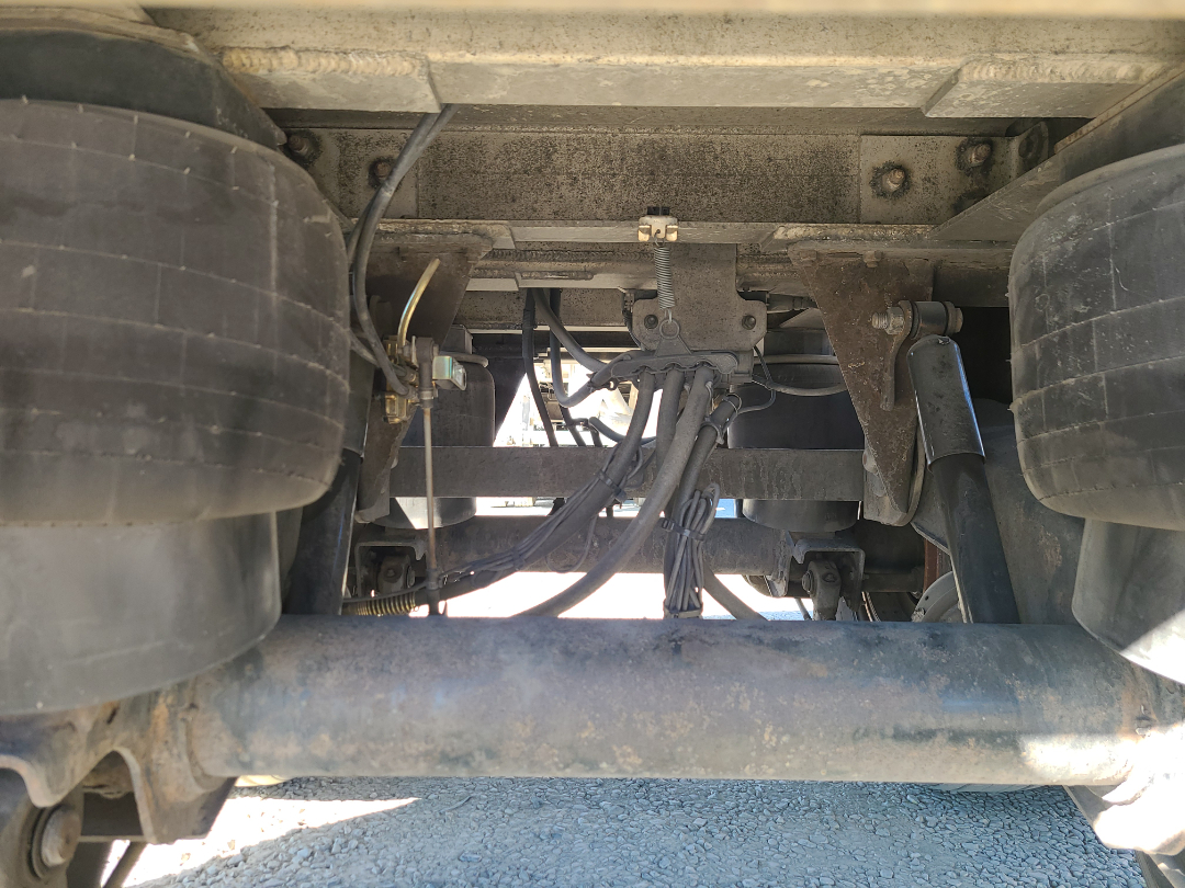 Undercarriage of a Beall trailer showing air lines, wiring, suspension, and dual rear axles with large tires.