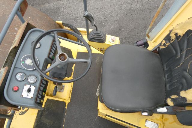 Cockpit view of Vibromax VM106D operator seat and steering wheel with dashboard gauges and control levers.