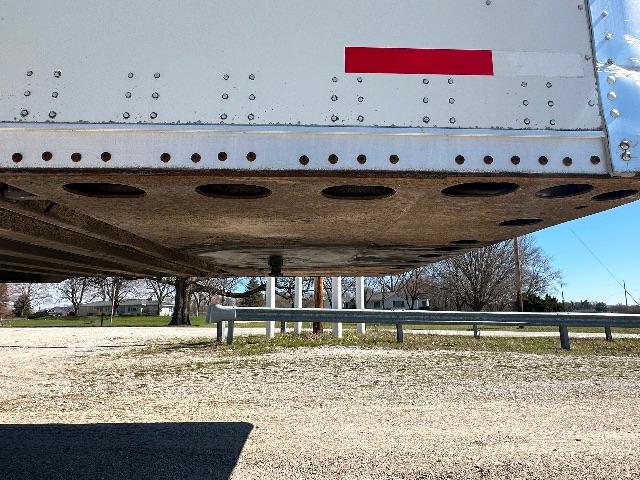 Vehicle trailer underside view showing circular cutouts and riveted metal side panel with a red reflector; part of a 2015 Wabash DuraPlate dry van.