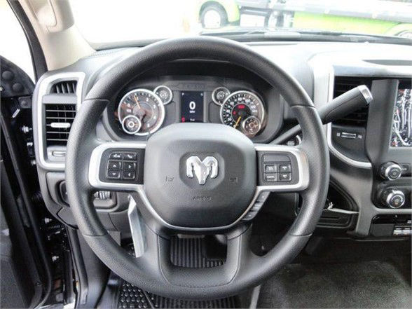 Ram steering wheel with Ram logo, dashboard gauges, and infotainment screen visible in a pickup truck interior.