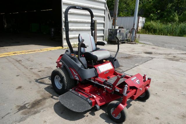 Red Ferris IS 700Z zero-turn mower with black roll bar, gray seat, and black foot pads. Visible text includes 'IS 700Z' on mower body and branding/stickers on deck.
