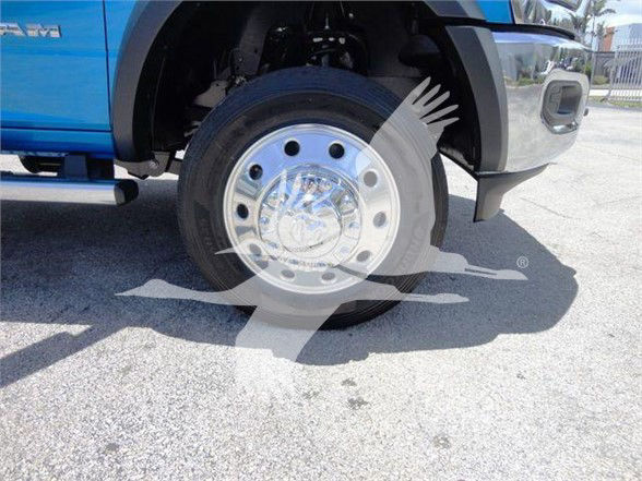 Front right wheel of a blue 2024 Ram 5500 SLT showing chrome wheel hub and tire with wheel well and fender.