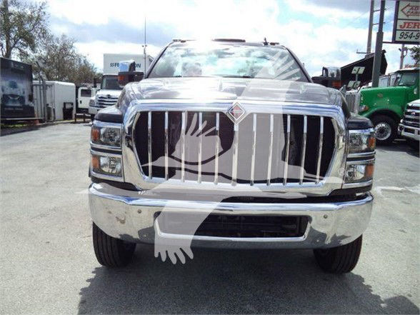 Front view of a shiny chrome International CV truck showing large vertical-bar grille and bumper, with headlights and logo, in a dealership lot.