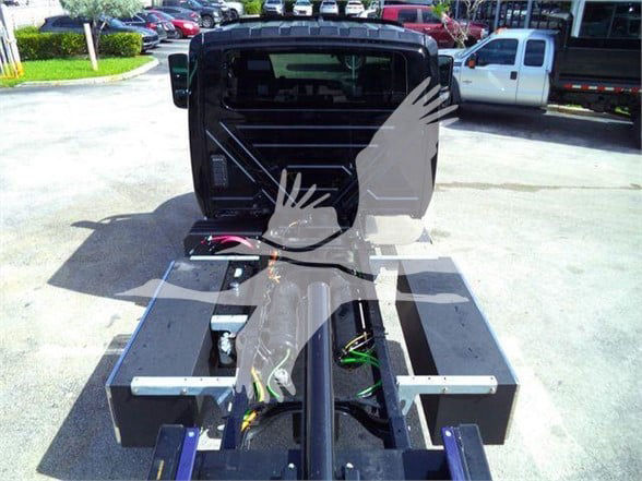 Tow truck chassis with exposed wiring and hydraulic components, rear view showing hitch and frame rails.