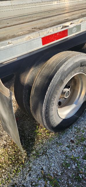 Dual axles trailer wheel and fender with treaded tire and aluminum wheel, utility combo flatbed side panel visible.