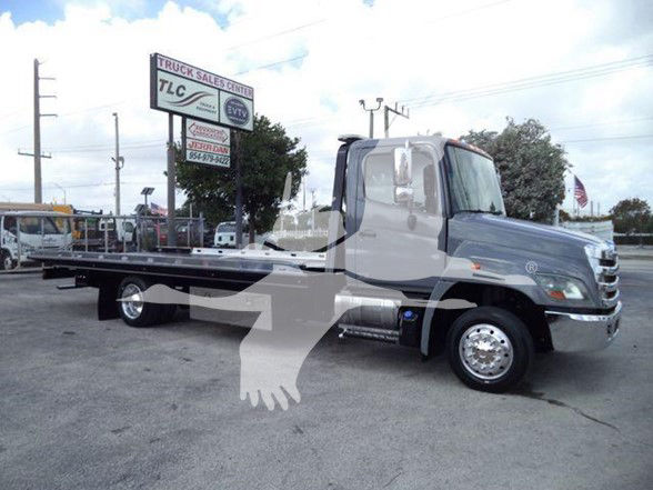 Flatbed tow truck 2014 Hino 258ALP with long low bed, gray cab, chrome wheels, and black flatbed; stock number T51352.