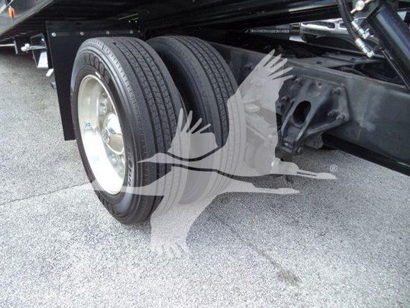Two large rear wheels of a Peterbilt truck chassis visible under a flatbed, with dual tires and suspension components.