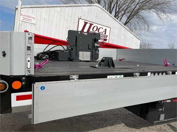 Trailer deck with equipment mounted, AA parts label, and stock yard background.