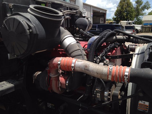 Peterbilt VN engine bay showing turbocharger, hoses, and radiator. Visible text on labels includes small warning sticker and nearby VIN plate not fully legible.