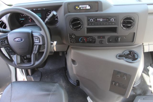 Ford dashboard interior showing steering wheel with Ford emblem, center console with radio/CD, climate controls, cup holder, and storage area.