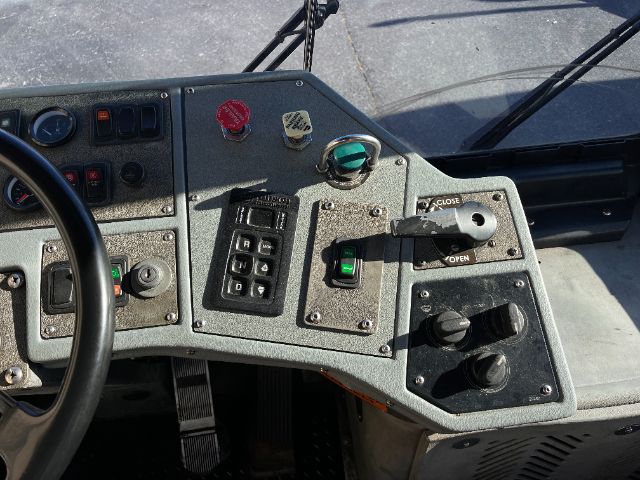 Dashboard of a yard truck showing switch panel, gauges, red and green knobs, and a lever with open/close label.