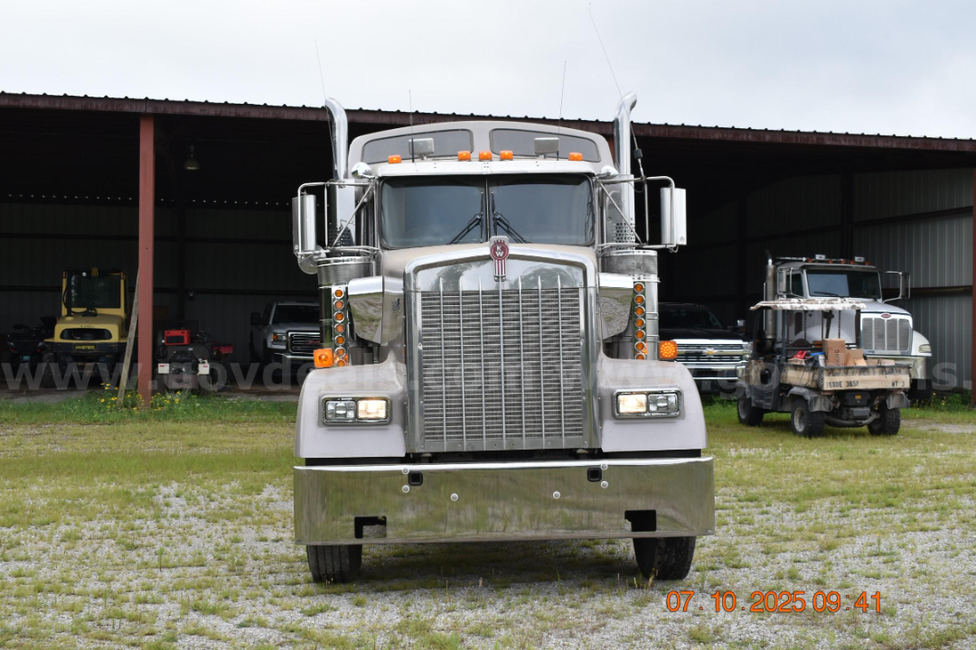 Kenworth W900 cab and chassis front view with large chrome grille, dual stacked headlights, and chrome bumper; visible large mirrors and hood ornament.