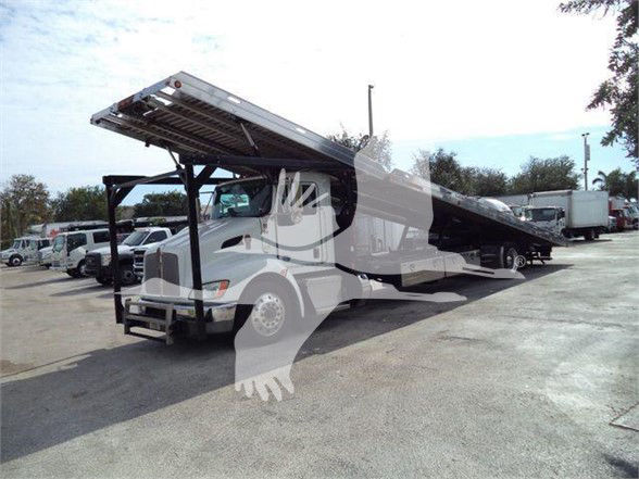 Kenworth T370 tow truck with raised flatbed/dump bed in service position.
