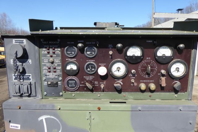 Panel of vintage truck equipment showing multiple gauges, switches, and a left-side control cluster on a military green console.