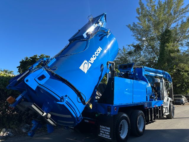 2005 Sterling L7500 vacuum truck on a flatbed trailer with blue crane arm and Vac-on branding visible.
