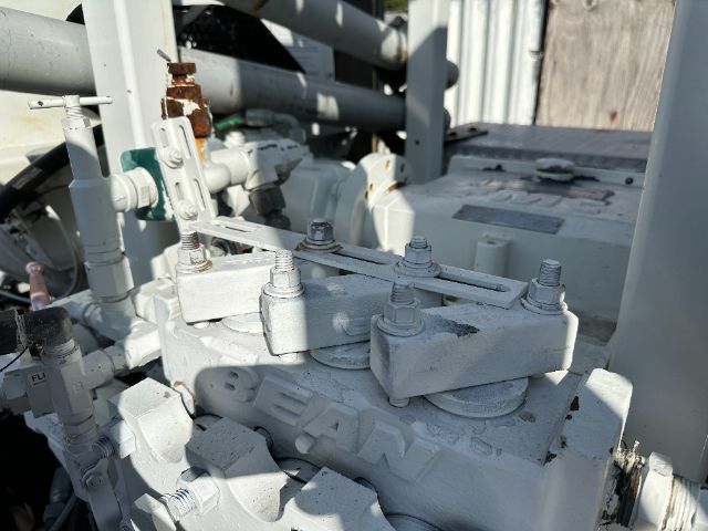 Freightliner 108SD engine bay with multiple bolts and hydraulic fittings on a white/gray component.