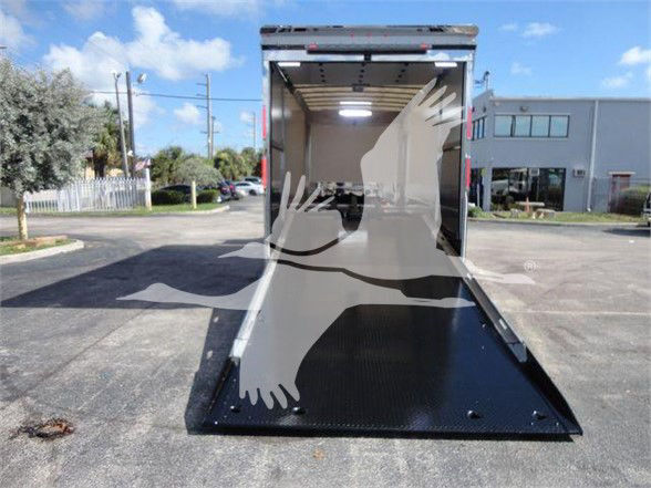 Open rear of a 2023 Mack MD6 tow truck with a lowered ramp, interior cargo area lit, and black anti-slip ramp surface.