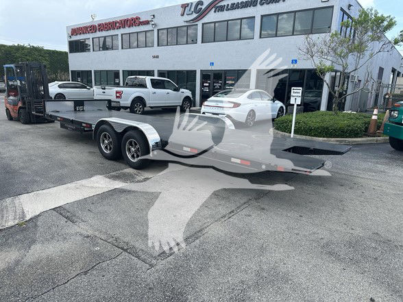 Flatbed trailer parked in front of TLC trailer leasing company building with dual-axle with aluminum deck and fenders; signage on building includes TLC Trailer Leasing Corp.