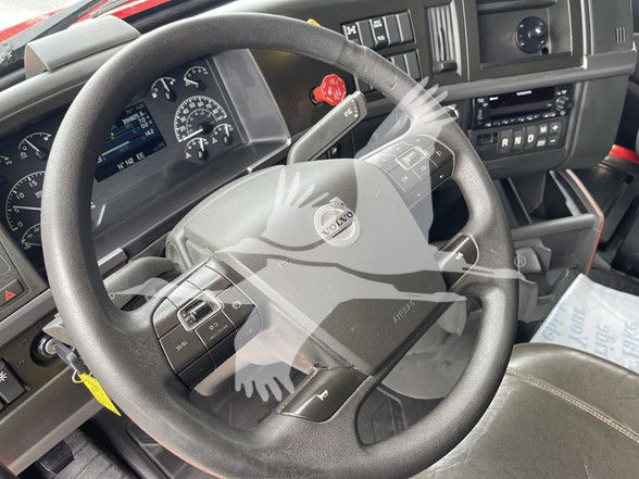  Volvo VNL64T740 truck interior showing steering wheel with Volvo emblem, dashboard gauges, gear shifter paddle, radio controls, and steering wheel buttons.