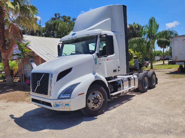 Truck cab image showing a white Volvo VNR daytime cab with trailer hitch and dual rear axles, front grille, and side mirrors.
