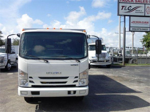 Isuzu NPR HD truck front view in white, cargo truck with large windshield and side mirrors, dealership lot in background.