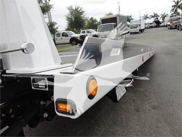 Ram 5500 tow truck with a flatbed and rear lights visible, side view showing bumper and wheel area.