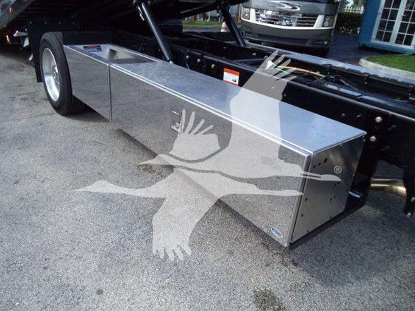 Aluminum toolbox mounted on the side of a truck chassis; rectangular metal box with clean seams and small fasteners, under-carriage perspective.
