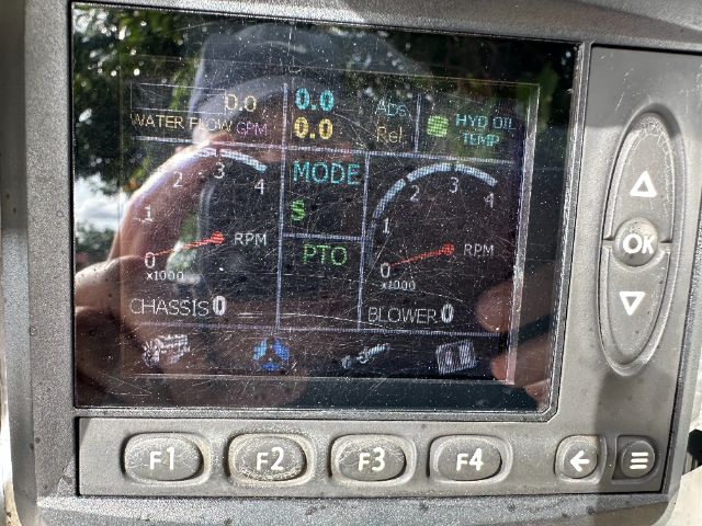 Dashboard display on a vehicle showing RPM gauges, mode indicators, and various readouts including water flow and hydraulic oil; appears to be from a cab console.