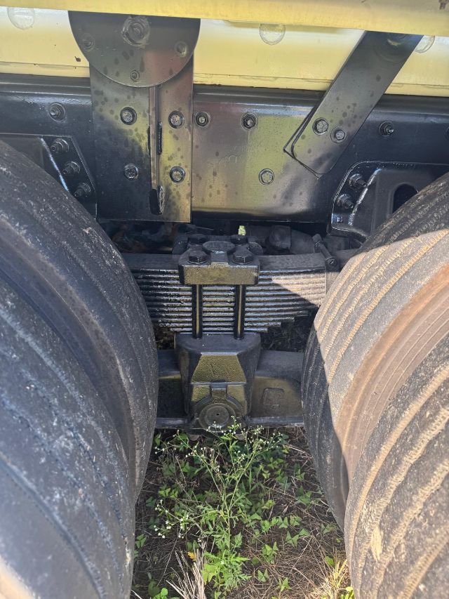 Dual rear wheels with sixth-wheel suspension and drive axle housing showing leaf springs and mounting hardware.