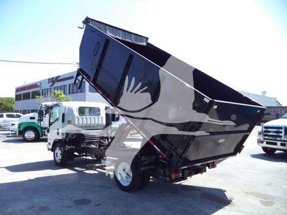 Isuzu NPR HD truck with a raised dump bed, side view showing dumping container and hydraulic lift, in a dealership lot.
