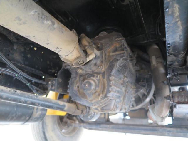 Truck undercarriage view showing drivetrain differential/ transfer case with driveline and suspension components.