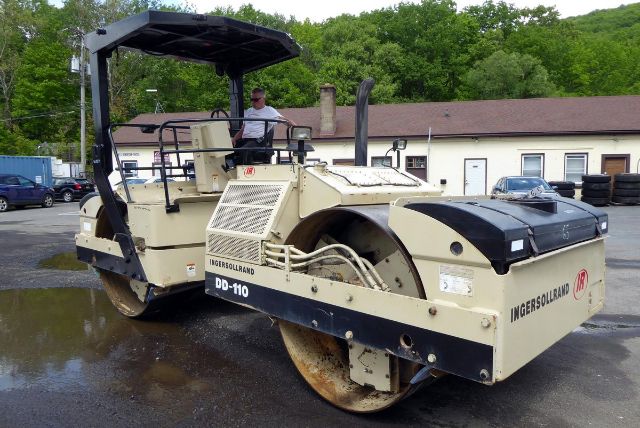 Ingersoll-Rand DD-110 road roller in a unloading lot showing operator seat and drum, with Ingersoll Rand branding and model DD-110.