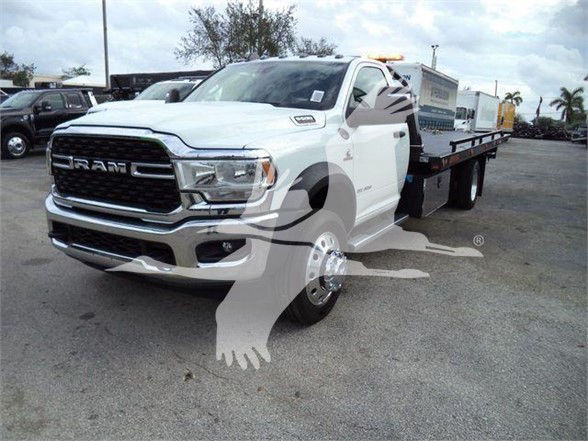 2024 Ram 5500 SLT tow truck with front grille RAM emblem, white cab, long flatbed on a dealership lot.