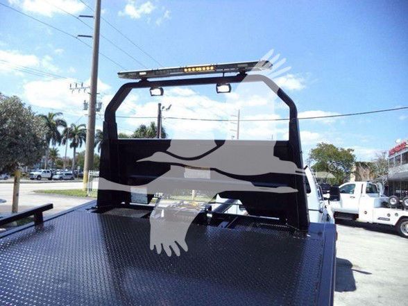Truck bed with headache rack and light bar on a flatbed, Ford F650 chassis cab style, rear view showing diamond plate steel bed.