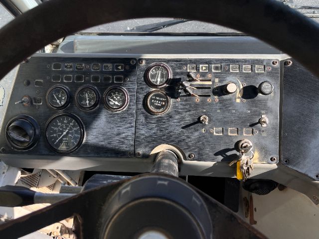 Dashboard panel of a Kalmar Ottawa yard truck showing multiple gauges, switches, and a steering column. Visible text includes various gauges and control labels on a metal dashboard.