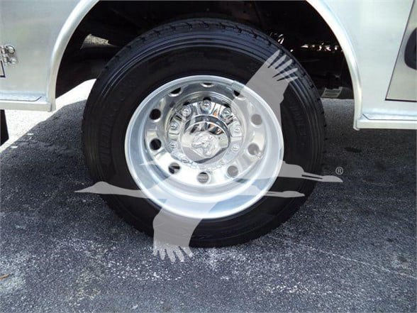 Ram 5500 wheel and tire on a pickup truck with chrome rim and hub, partial silver body panel visible.