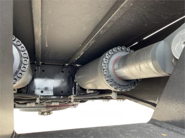 Trailer underside with roller bearings and suspension components visible. Text not clearly legible.