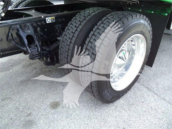 Tow truck rear dual wheel assembly with whitewall tires and chrome rims; visible frame and suspension components; small label sticker on chassis.