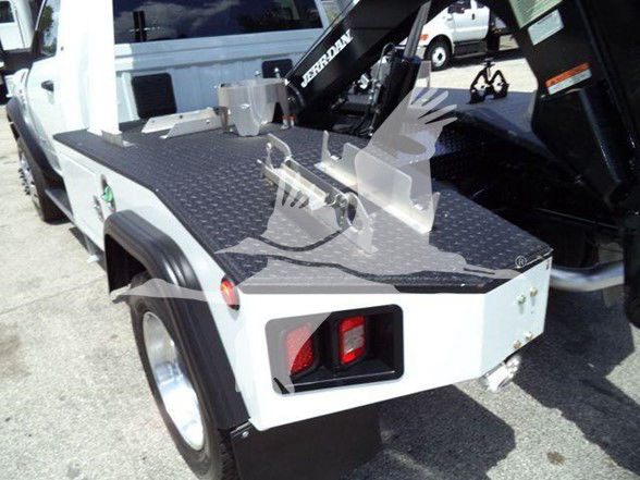 Ram 4500 tow truck rear deck with diamond plate surface and hitch; taillight visible; crane arm labeled 'BROMANN' near cab.