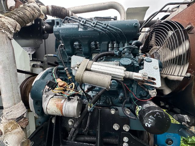 Isuzu NPR-HD engine bay showing diesel engine with mounted alternator, wiring, and components; cooling fan visible on right; various hoses and metal brackets.