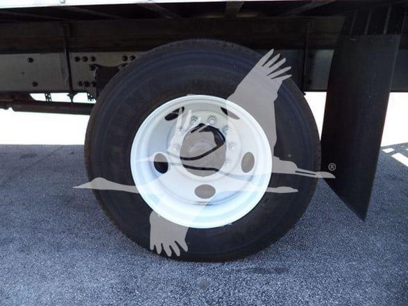 Wheel of a 2016 International Business Class M2 106 series truck, white steel rim with black tire, undercarriage visible.
