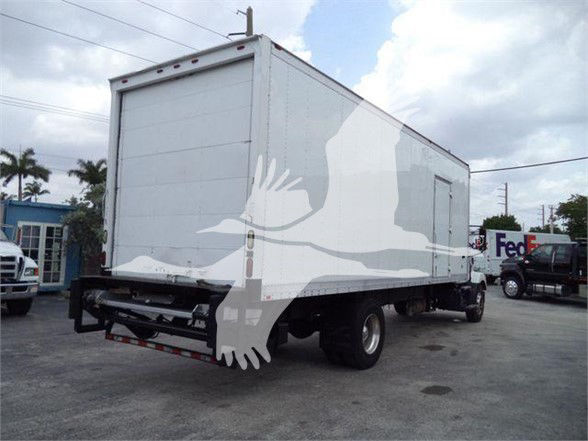 Box truck rear three-quarter view showing cargo box and chassis with FedEx in background.