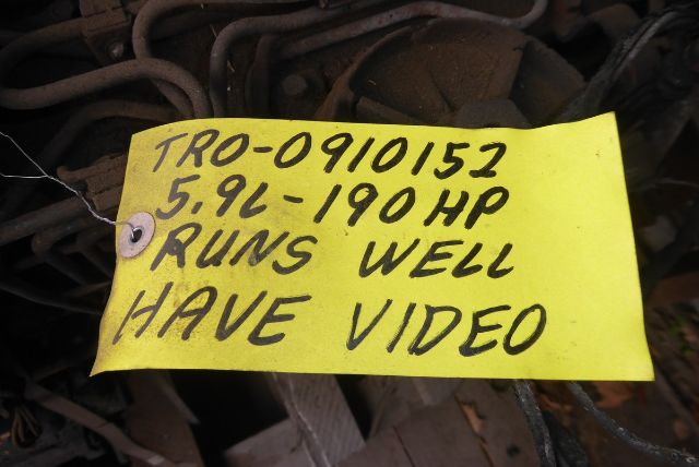 Engine bay tag note reading 'TRO-0910152 5.9L-190HP RUNS WELL HAVE VIDEO' with surrounding hoses and engine components.